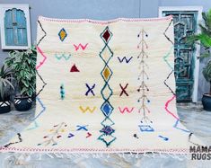 a multicolored rug on display in front of potted plants and other items