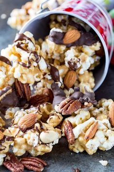 chocolate covered popcorn with nuts and pecans on the table next to an open can