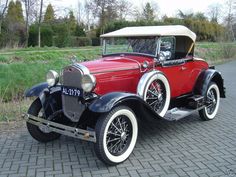 an old red and white car is parked on the street