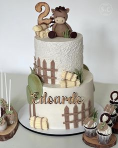 a three tiered cake with cupcakes and decorations