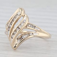 a yellow gold ring with white diamonds on the top and bottom, sitting on a wooden surface