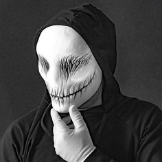 a man in a black hoodie with his face painted like a creepy mask and hands on his chin