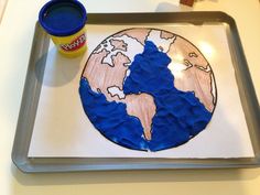 the earth is made out of paper on a tray next to a cup of paint