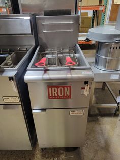 two commercial fryers sitting next to each other on the floor in a kitchen area