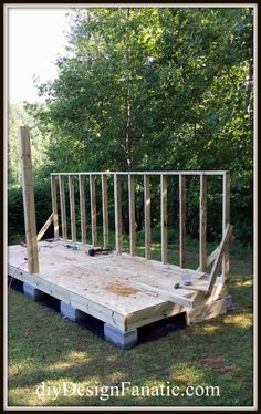 a wooden platform with metal bars on it in the grass