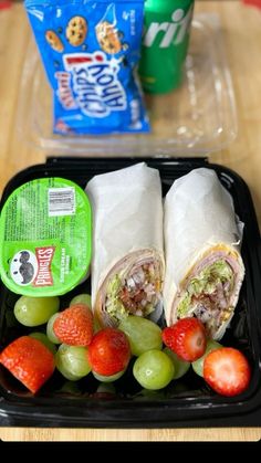 a lunch box with fruit, sandwich wrap and yogurt