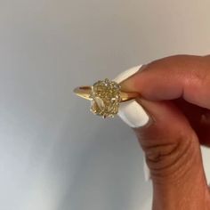 a person holding a yellow diamond ring in their hand