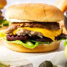 a cheeseburger with meat, lettuce and pickles on the side