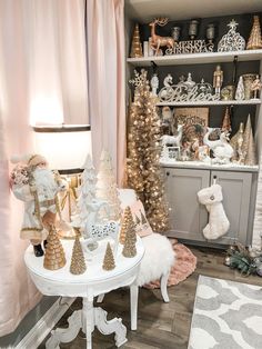 a white table topped with lots of christmas trees and other holiday decorations in a living room