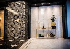 a black and white wall in a room with a gold shelf next to it on a marble floor