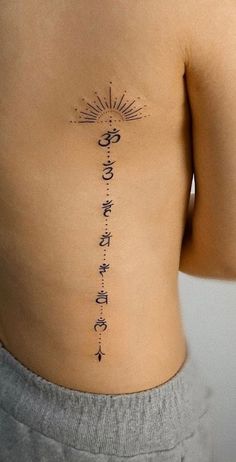 the back of a woman's stomach with an arrow and sun tattoo on it