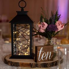 a wooden sign that says ten on it next to a vase with flowers and lights