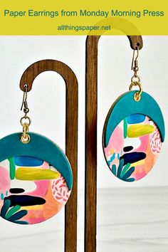 paper earrings from monday morning press are hanging on a wooden stand with text overlay that reads paper earrings from monday morning press