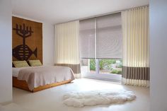 a bed room with a neatly made bed next to a window and a rug on the floor