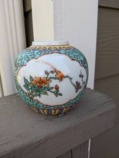 a decorative vase sitting on top of a wooden table next to a window sill