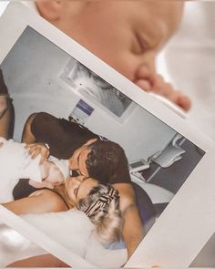 a man and woman holding up a polaroid with a baby in it's lap