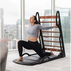 a woman is doing yoga on an exercise mat in front of a window with the cityscape behind her