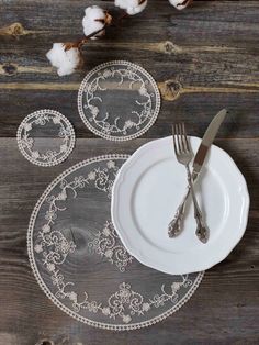 a white plate topped with two silverware next to cotton floss on top of a wooden table