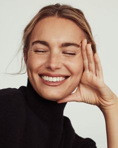 a woman smiling and holding her hands to her face