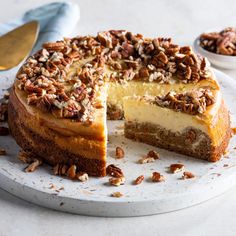 a cheesecake with pecans on top sits on a plate