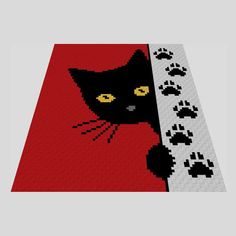 a black cat is peeking out from behind a red rug with paw prints on it