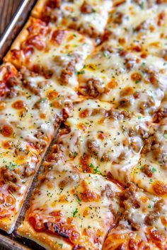 a close up of a pizza with cheese and meat toppings in a pan on a wooden table