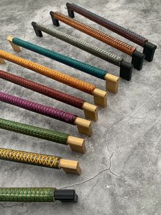 seven different colored wooden handles on top of a stone surface with one black handle in the middle