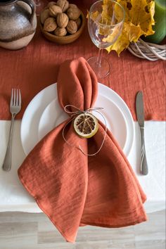 an orange napkin on top of a white plate