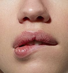 a woman's lips are shown with the tip of her lip sticking out to the side