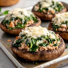 baked stuffed mushrooms with spinach, cheese and other toppings on a baking sheet