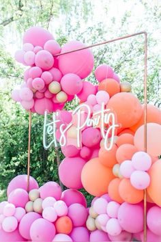 pink and orange balloons are hanging from a metal frame with the words let's party written on it