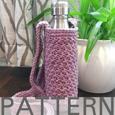 a crocheted water bottle cover sitting next to a potted plant