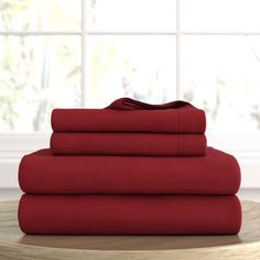 a stack of red sheets sitting on top of a wooden table