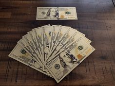 five hundred dollar bills laid out on a wooden table