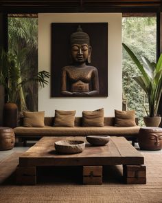 a living room filled with furniture and a buddha statue hanging on the wall above it