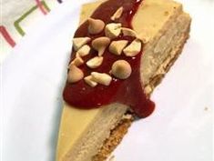 a piece of cheesecake on a plate with sauce and nuts in the top layer