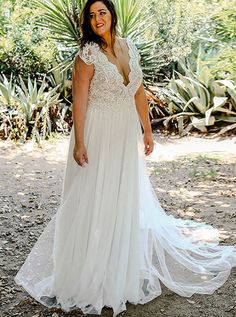 a woman wearing a white dress standing in front of some plants