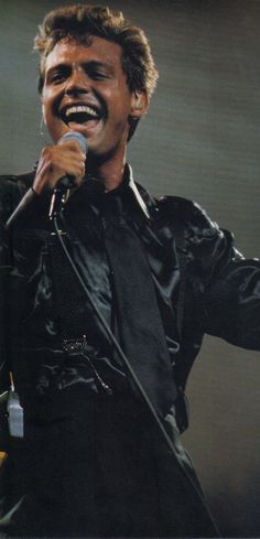 a man singing into a microphone on stage