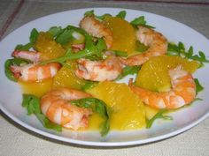 a white plate topped with shrimp and veggies on top of a table cloth