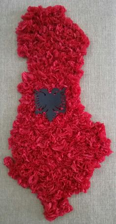 a teddy bear made out of red yarn with a black cat on it's chest