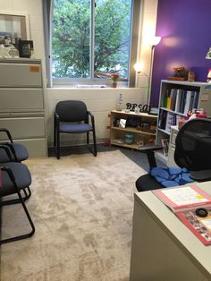 a room with two chairs, a desk and a book shelf in it's corner