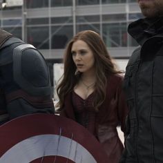 captain america the winter soldier is standing next to two other people in front of a building