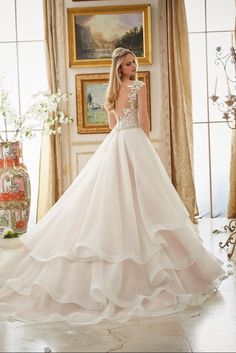 a woman in a white wedding dress standing by a window