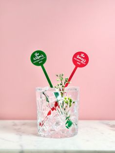 two red and green stickers sticking out of a glass filled with ice cubes