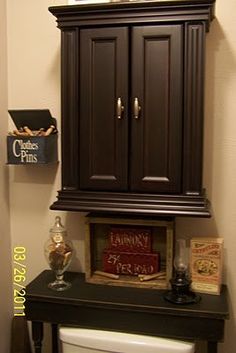 a bathroom with a toilet, cabinet and other items on the shelf above the toilet