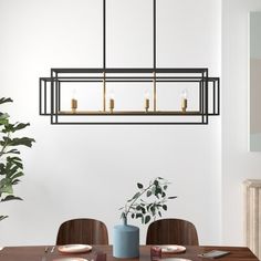 a dining room table and chairs with a plant in the corner on one side, two candles on the other