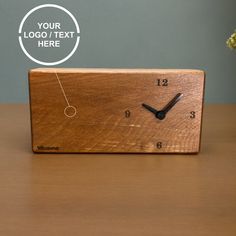 a wooden clock sitting on top of a table next to a vase filled with flowers