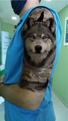 a man with a wolf tattoo on his arm is holding up the sleeve of his shirt