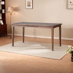 a wooden table sitting on top of a hard wood floor next to a book shelf