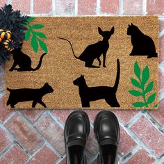 a pair of black shoes sitting on top of a door mat with cats and dogs